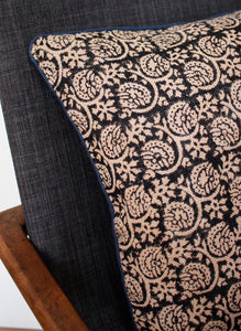 Corner of black block printed cushion with blue piping