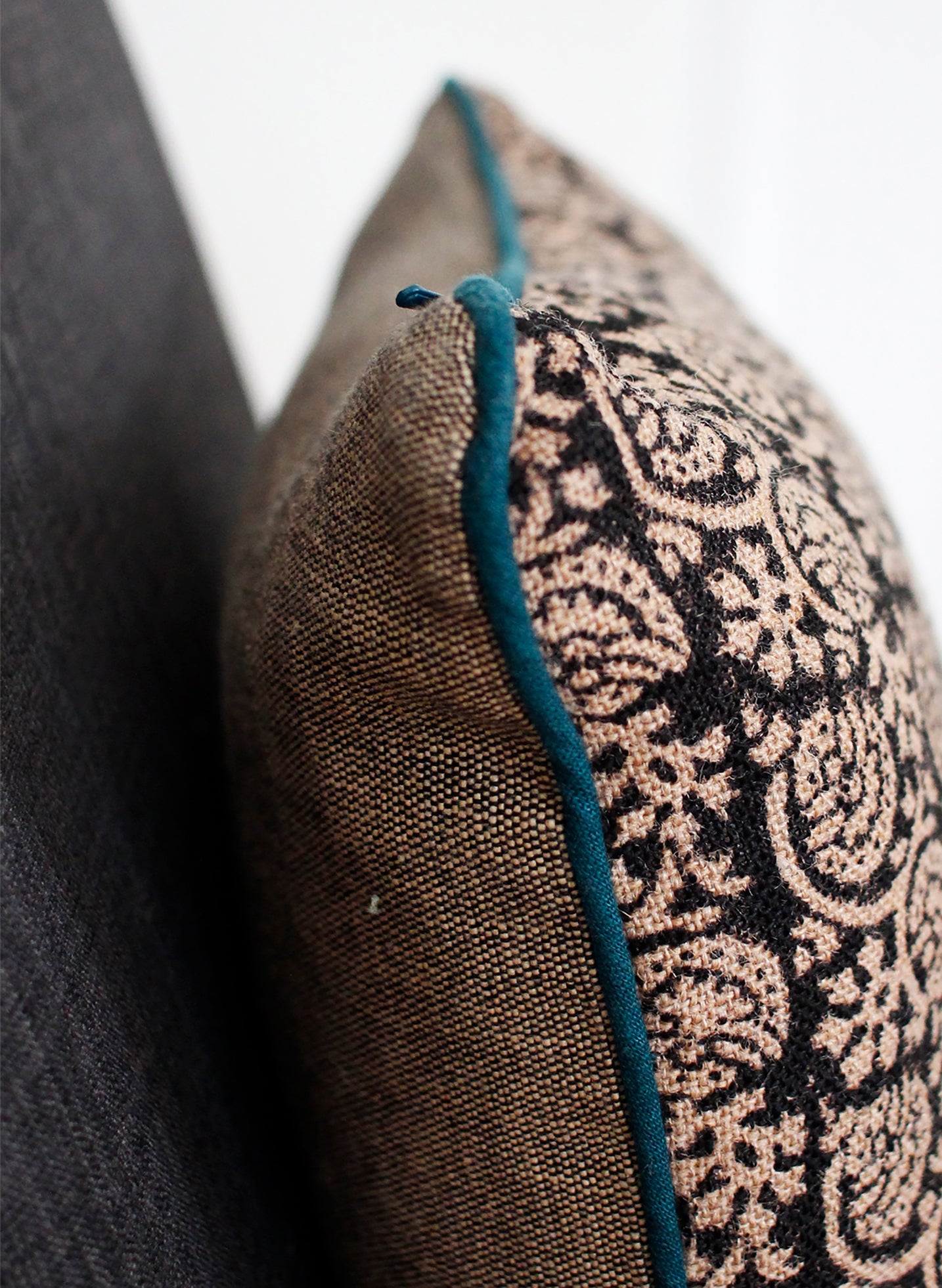 Detail of black jute cushion cover with teal piping 