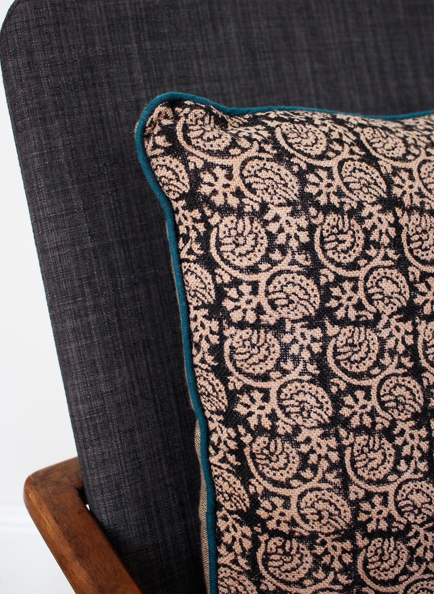 Detail of black floral cushion cover with teal piping 
