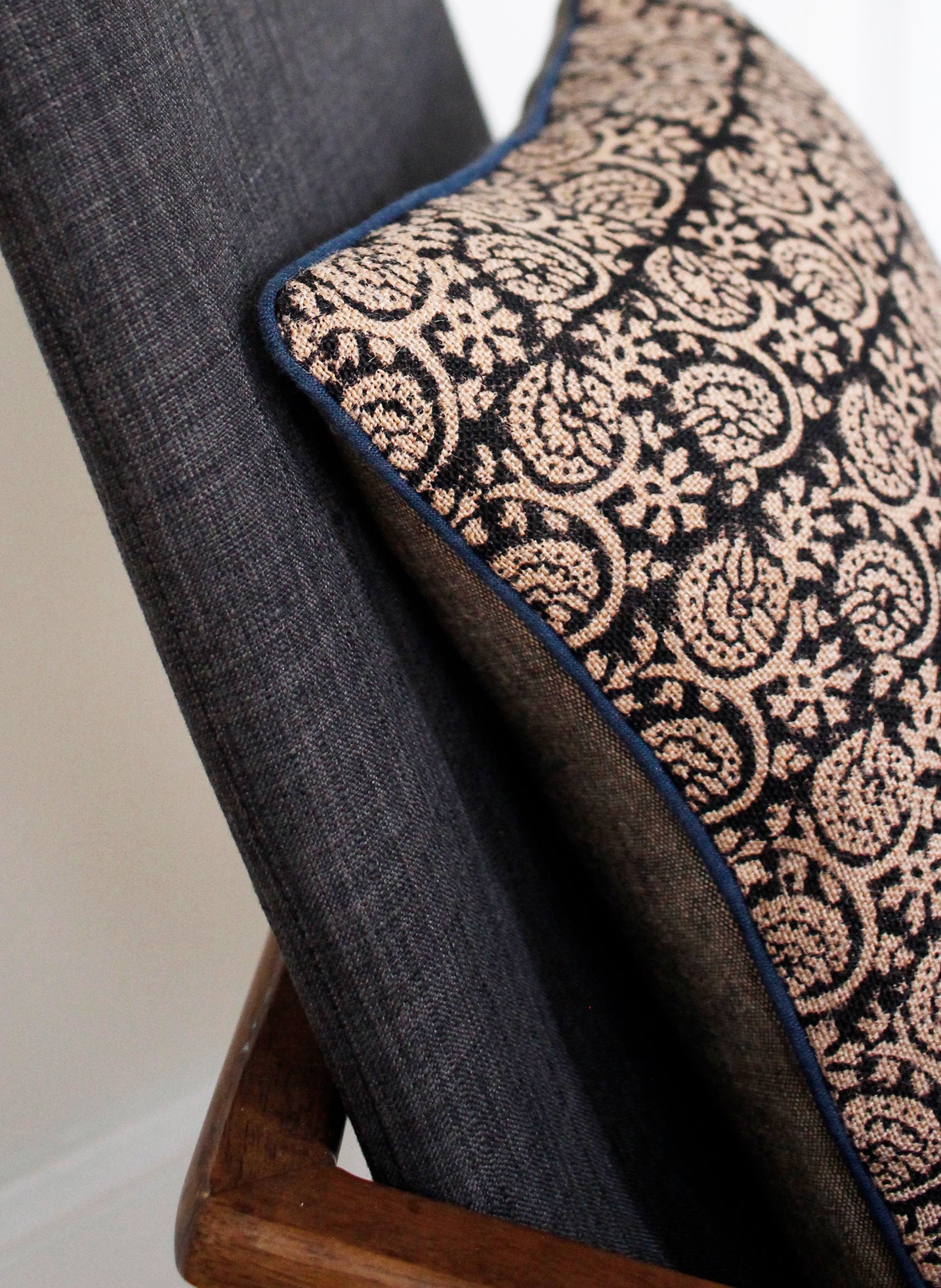 Detail of black floral cushion cover with blue piping 