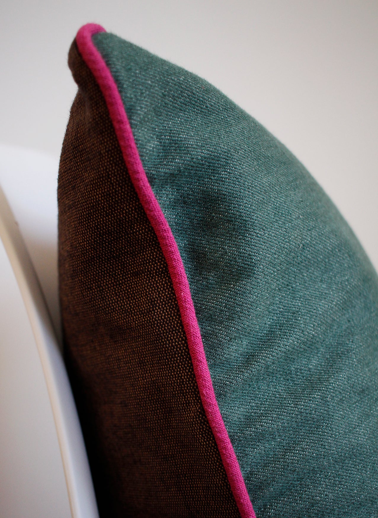 Detail of green denim cushion with pink piping