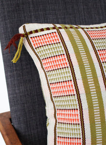 Corner detail of coral and green handwoven cushion with small tassels