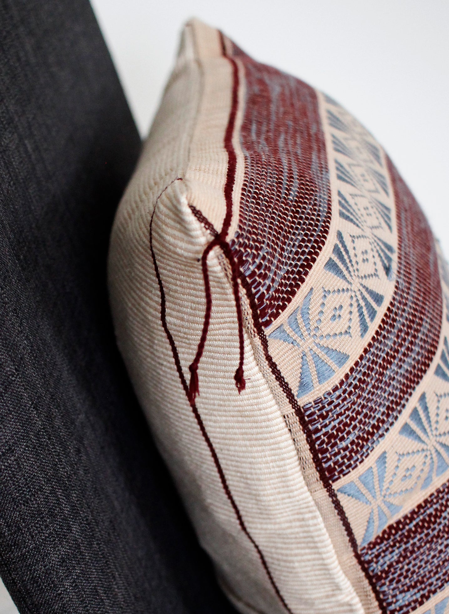 Detail of handwoven cushion in black and red pattern with tassel on the corner