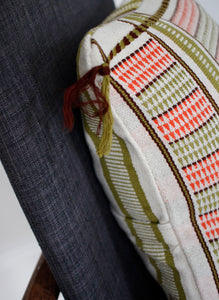 Corner detail of green and coral handwoven cushion with tassel