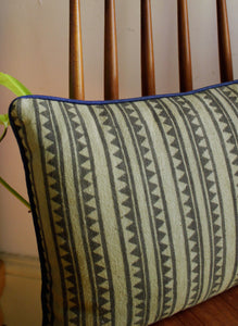 Detail of olive green cotton cushion cover with  black geometric print and blue piping