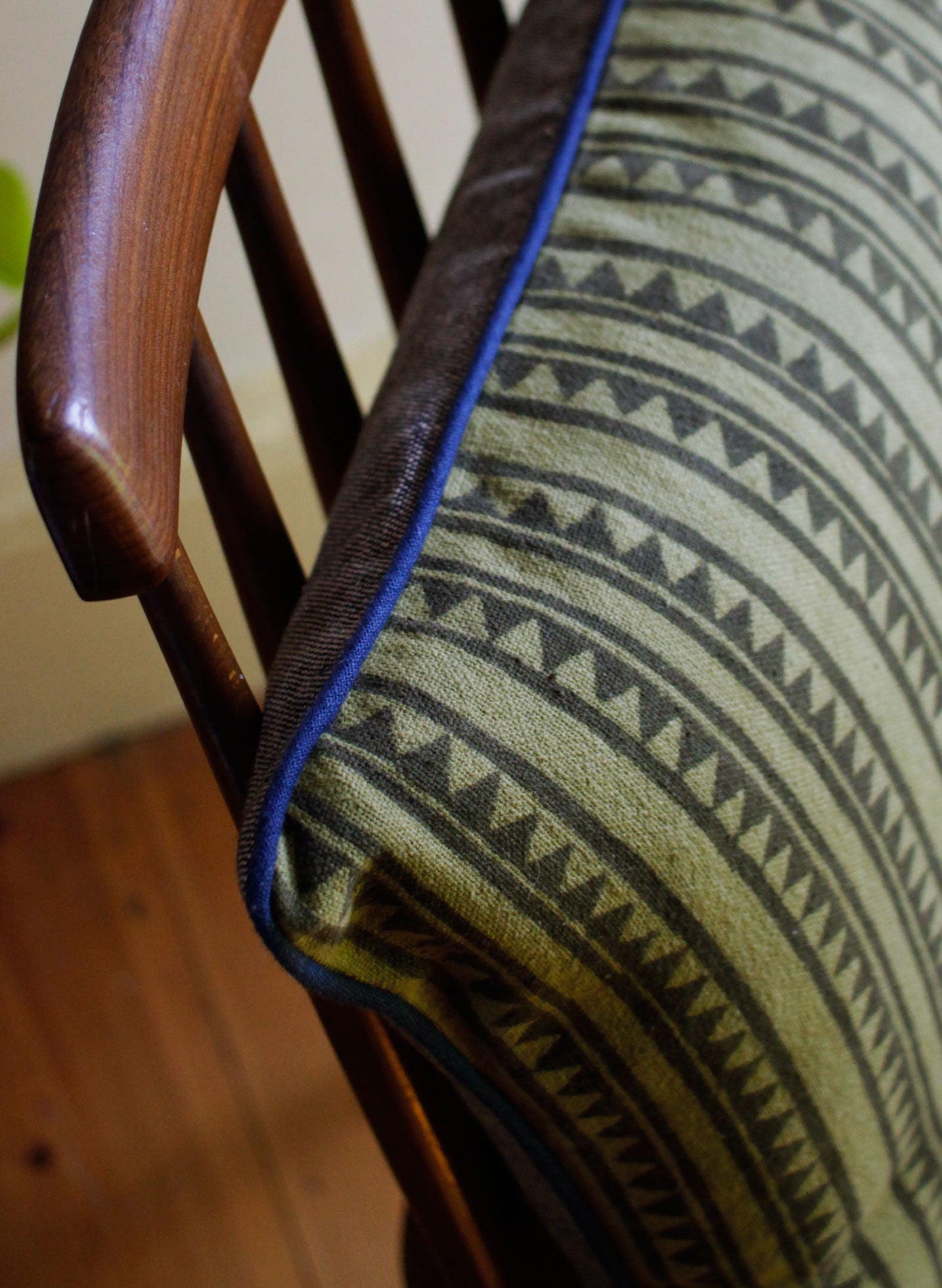 Detail of geometric print on cotton cushion with contrasting blue piping 